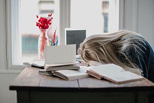 Erschöpfte Studentin liegt mit dem Kopf auf dem Tisch